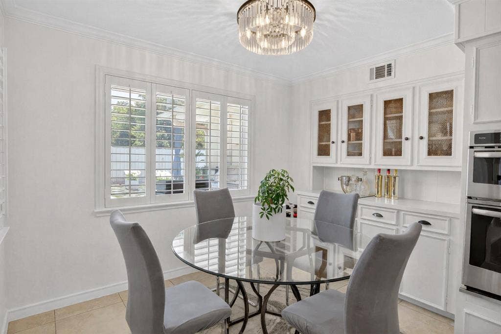 Dining room featuring a chandelier, crown molding, and light tile patterned flooring