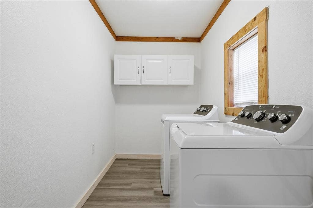 1116 Houston Street, Waco, TX 76704 Laundry area featuring independent washer and dryer, light wood-type flooring, cabinet space, and crown molding