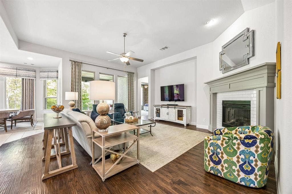 The family room perfectly balances grand scale with everyday comfort. Anchored by gorgeous hardwoods, the space centers around an elegant fieplace featuring a craftsman manetl and classic subway tile surround. Wall to wall windows with high-end custom draperies frame serene, tree-lined views. The space accomodates oversized furnishings.