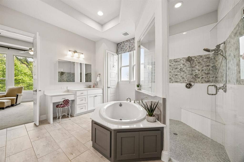 Luxurious , spa-inspired primary ensuite. The meticulously deisgned space features a massive frameless glass walk-in shower adorned with premium tile accents and dual shower heads. A deep soaking tub offers the perfect spot to unwind after a long day.