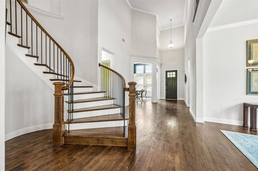 High soaring ceilings create an immediate sense of scale, airiness, and sophisticated luxury. The flowing curved staircase featuring wood treads and crisp white risers creat a dramatic focal point in the home.