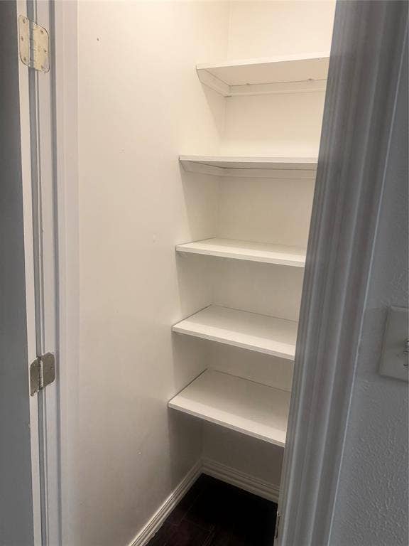 2301 Holly Drive, Euless, TX 76039 Built-in shelving unit with five white shelves, white baseboards, and dark wood-finish flooring
