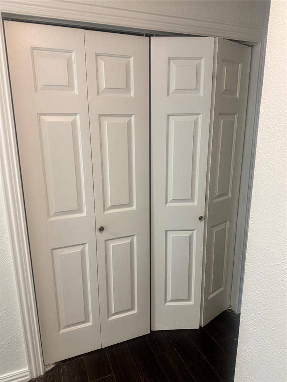 2301 Holly Drive, Euless, TX 76039 White bi-fold doors featuring panel detailing, dark wood-finish flooring, and white trim