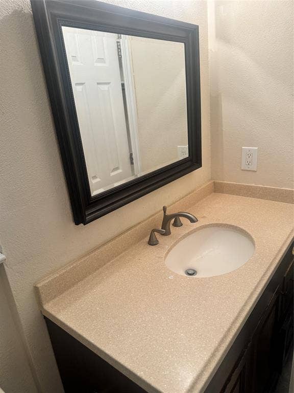 2301 Holly Drive, Euless, TX 76039 Vanity featuring a speckled light-toned countertop with integrated backsplash, oval undermount sink, and a dark bronze finish faucet