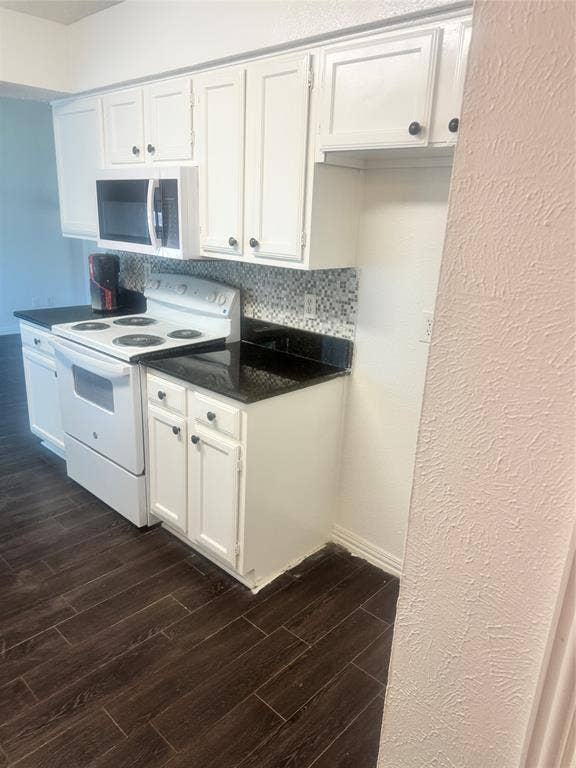 2301 Holly Drive, Euless, TX 76039 Kitchen featuring white cabinetry, black countertops, a mosaic tile backsplash, and dark wood-finish flooring