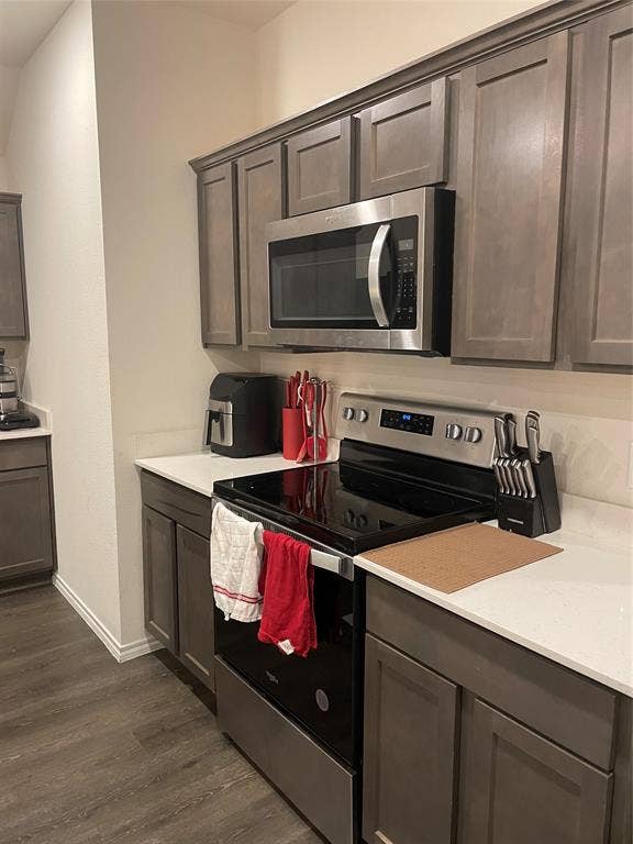 468 Unbridled Road, Waxahachie, TX 75165 Kitchen featuring stainless steel appliances, dark wood-style floors, light stone counters, and dark wood finish cabinets