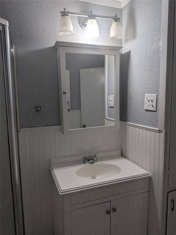 2009 County Road 4619, Athens, TX 75752 Bathroom with a textured wall, vanity, and wainscoting