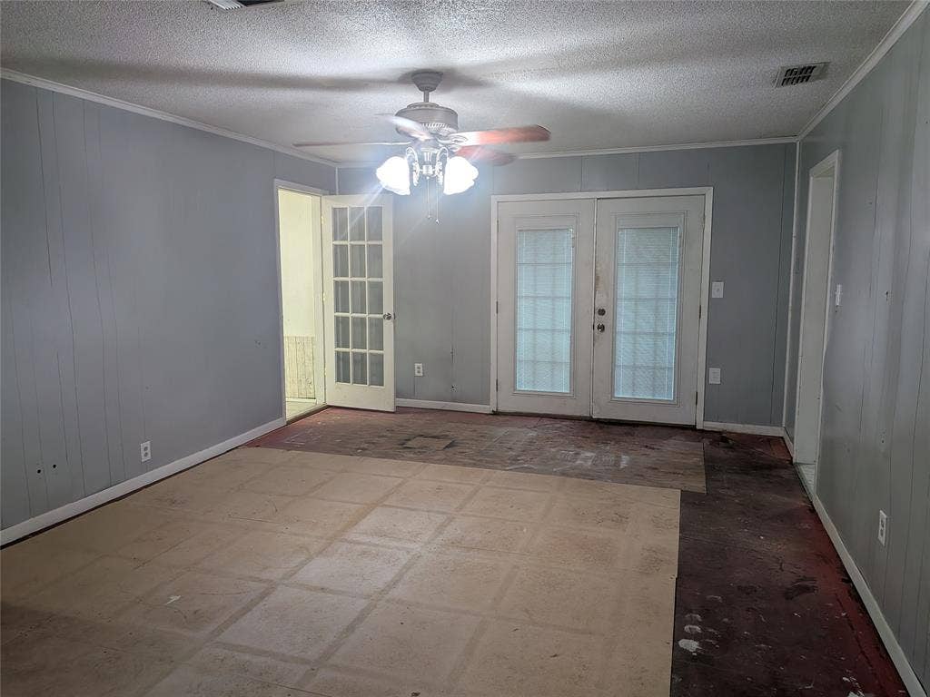 2009 County Road 4619, Athens, TX 75752 Empty room with french doors, crown molding, a ceiling fan, a textured ceiling, and wooden walls