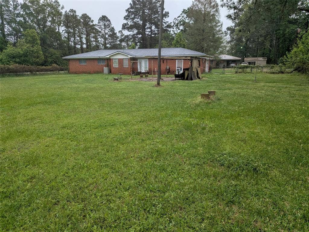 2009 County Road 4619, Athens, TX 75752 Rear view of property featuring a lawn, view of wooded area, and brick siding