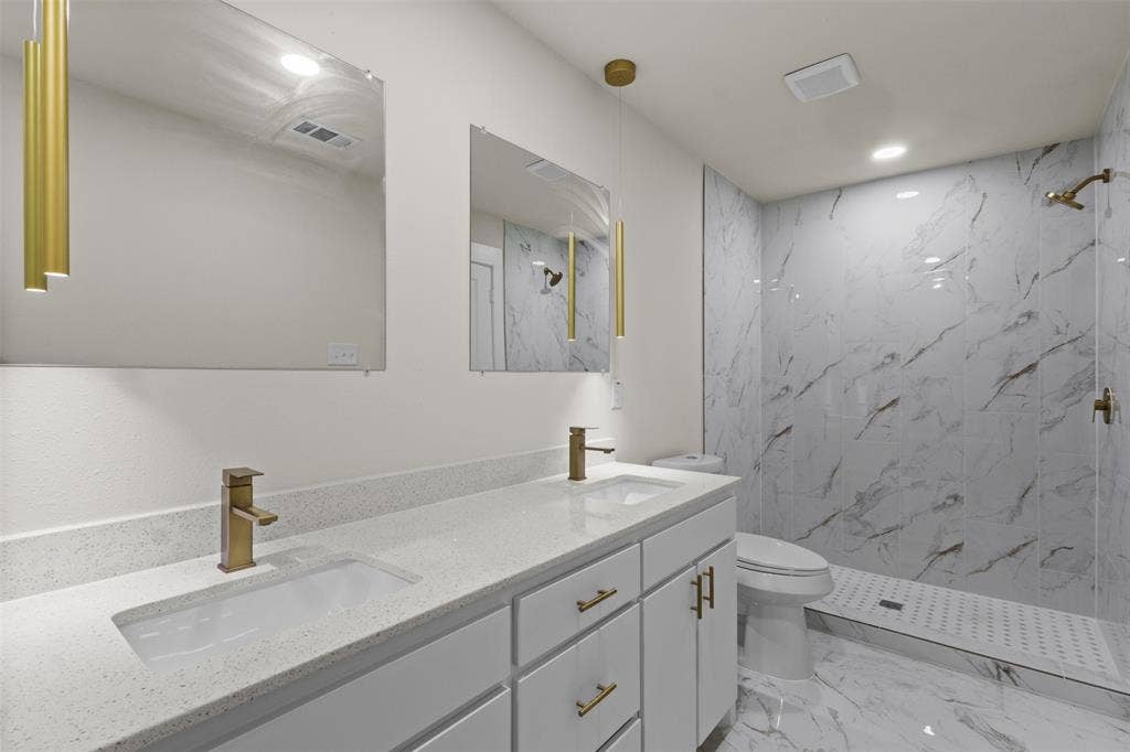 425 Browning Drive, Arlington, TX 76010 Bathroom featuring a dual vanity with light grey cabinetry and white countertops, under-mount sinks with brass-finish faucets, and two rectangular mirrors