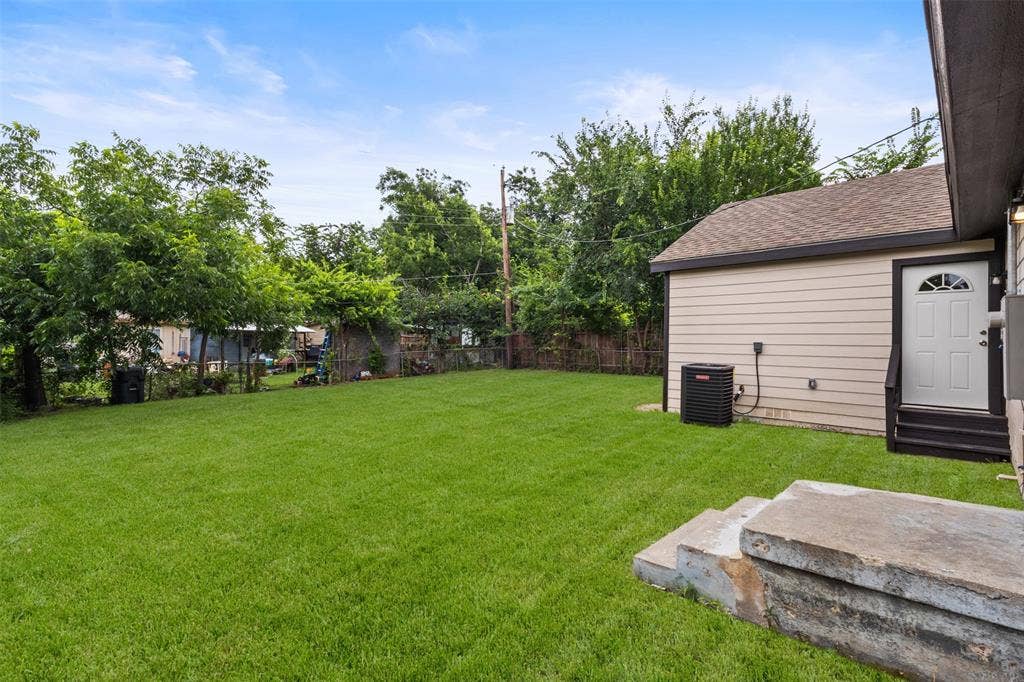 425 Browning Drive, Arlington, TX 76010 Expansive grassy backyard featuring mature perimeter trees, a concrete patio, and a utility access door