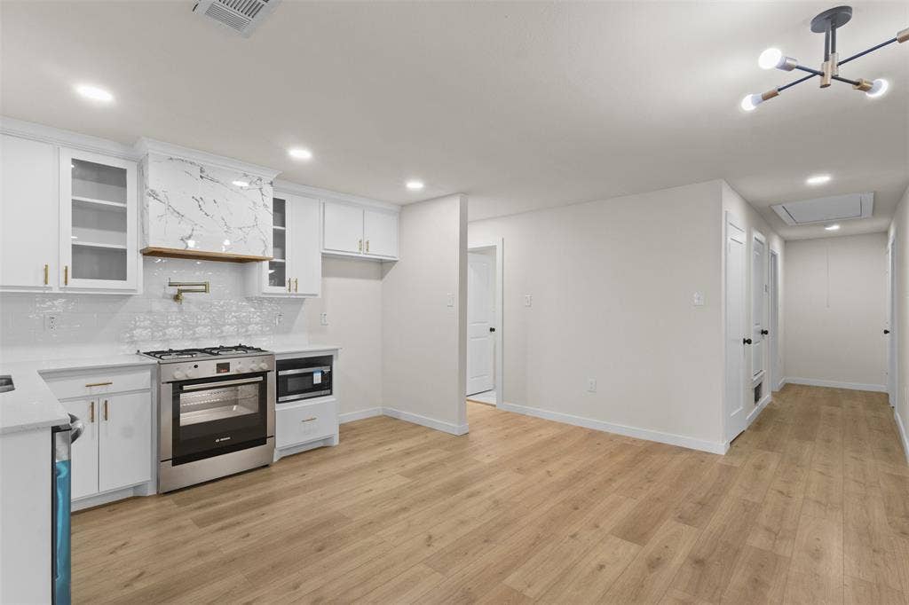 425 Browning Drive, Arlington, TX 76010 Contemporary kitchen with white cabinetry, stainless steel range and microwave, light wood-finish flooring, and recessed lighting