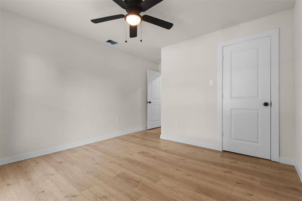 425 Browning Drive, Arlington, TX 76010 Bedroom featuring wood-finish flooring, light-colored walls, white baseboards, and a black ceiling fan with an integrated light fixture