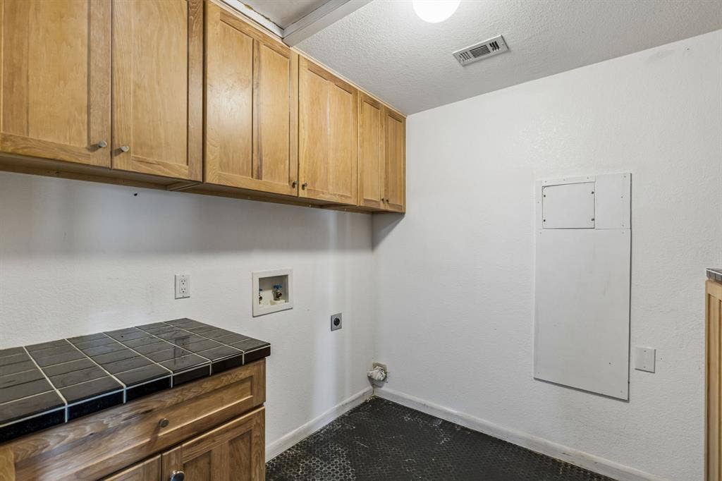 6360 Curtis Street, Plano, TX 75093 Separate full size washer and dryer laundry room near the kitchen with tile flooring. and built in cabinets.
