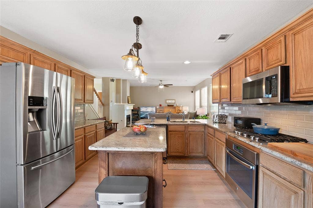 1608 Mountain Laurel Drive, Keller, TX 76248 Kitchen featuring light wood-finish cabinetry, stainless steel appliances, speckled countertops, and a subway tile backsplash