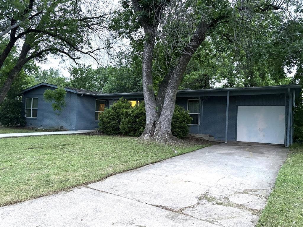 2829 Cecil Drive, Richland Hills, TX 76118 The property features a blue exterior with a white garage door, a concrete driveway, and a well-maintained lawn
