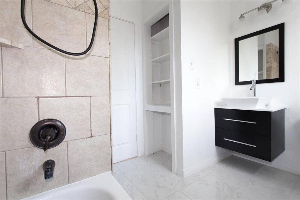 2829 Cecil Drive, Richland Hills, TX 76118 Contemporary floating vanity with a rectangular vessel sink, wall-mounted faucet, and black framed mirror