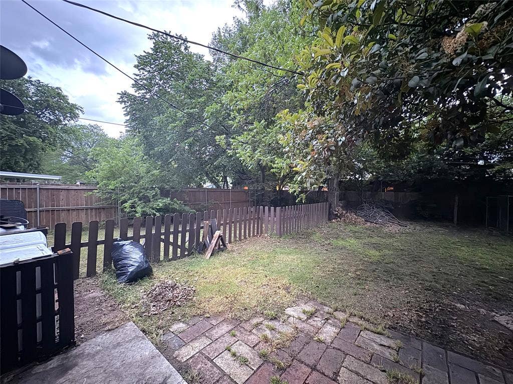 2829 Cecil Drive, Richland Hills, TX 76118 Expansive backyard featuring a partial brick paver patio, a partial picket fence, and mature trees providing natural shading