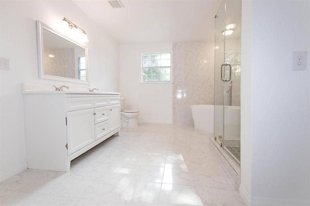 2829 Cecil Drive, Richland Hills, TX 76118 Full bathroom featuring a white dual vanity with undermount sinks, a frameless glass shower enclosure, a freestanding soaking tub, and large format floor tiling