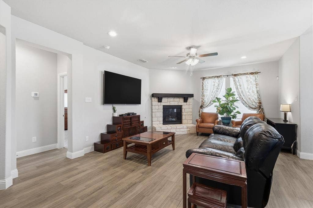 Living area is warm and inviting with a stone fireplace and backyard views