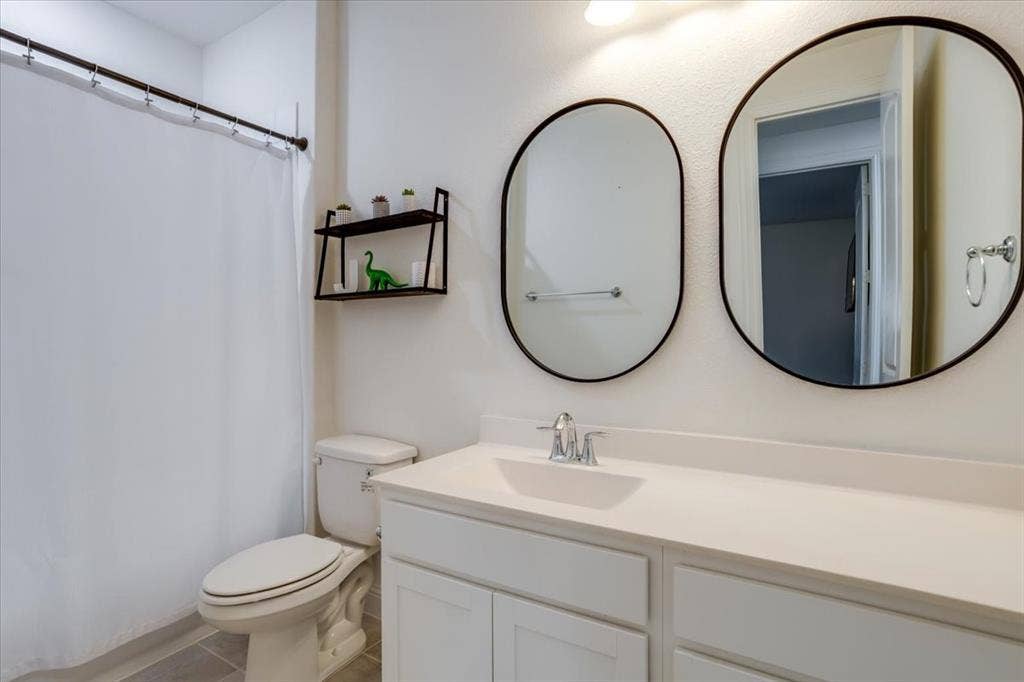 Full bathroom featuring vanity, a shower with shower curtain, and light tile patterned flooring