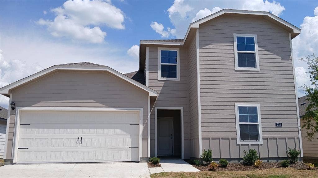 223 Whispering Pine Drive, Royse City, TX 75189 Two-story residence featuring light beige siding and a prominent two-car garage with decorative hardware