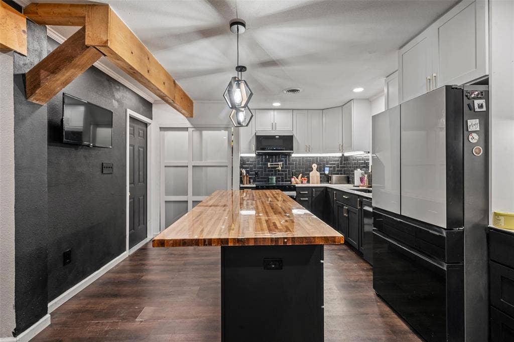 1207 Pembrook Drive, Waco, TX 76710 The kitchen features a spacious butcher block island, dark wood flooring, and modern pendant lighting