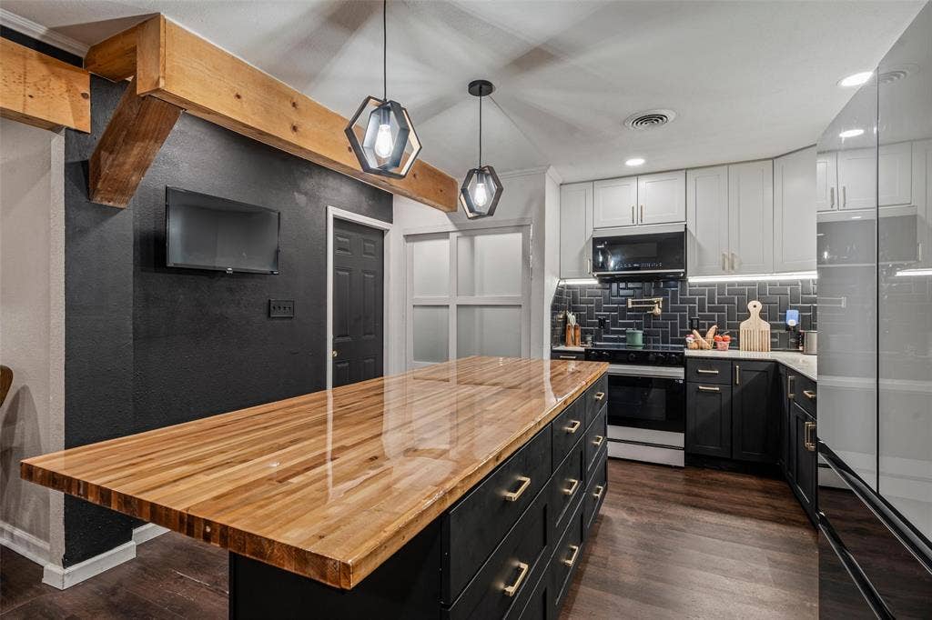1207 Pembrook Drive, Waco, TX 76710 The kitchen features a spacious island with a polished wood countertop, two pendant lights, and dark wood flooring