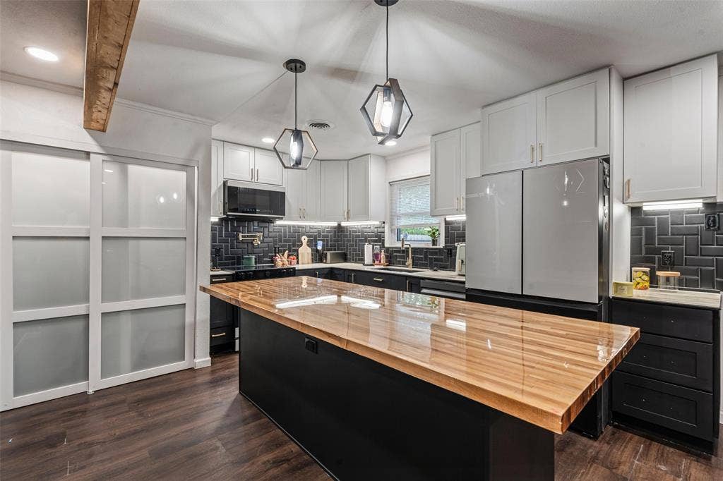 1207 Pembrook Drive, Waco, TX 76710 The kitchen features a large island with a wooden countertop, pendant lighting, hardwood flooring, and white upper cabinetry