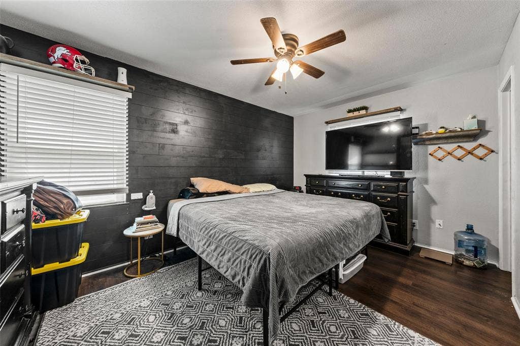 1207 Pembrook Drive, Waco, TX 76710 Bedroom featuring an accent wall, dark wood-style floors, ceiling fan, and wooden walls