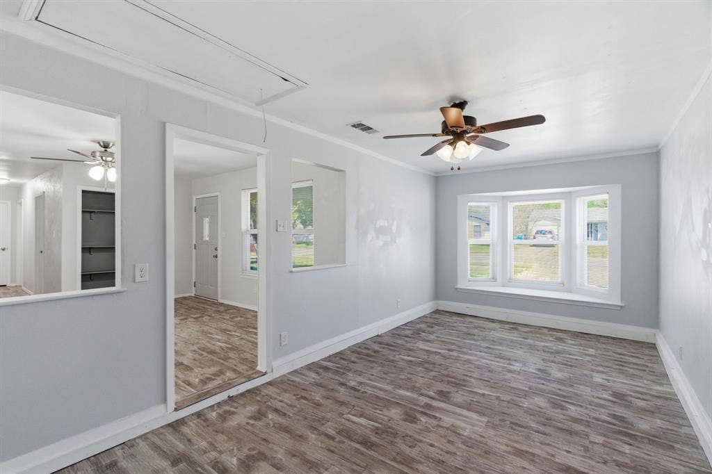 Spare room with ceiling fan, wood finished floors, plenty of natural light, and crown molding