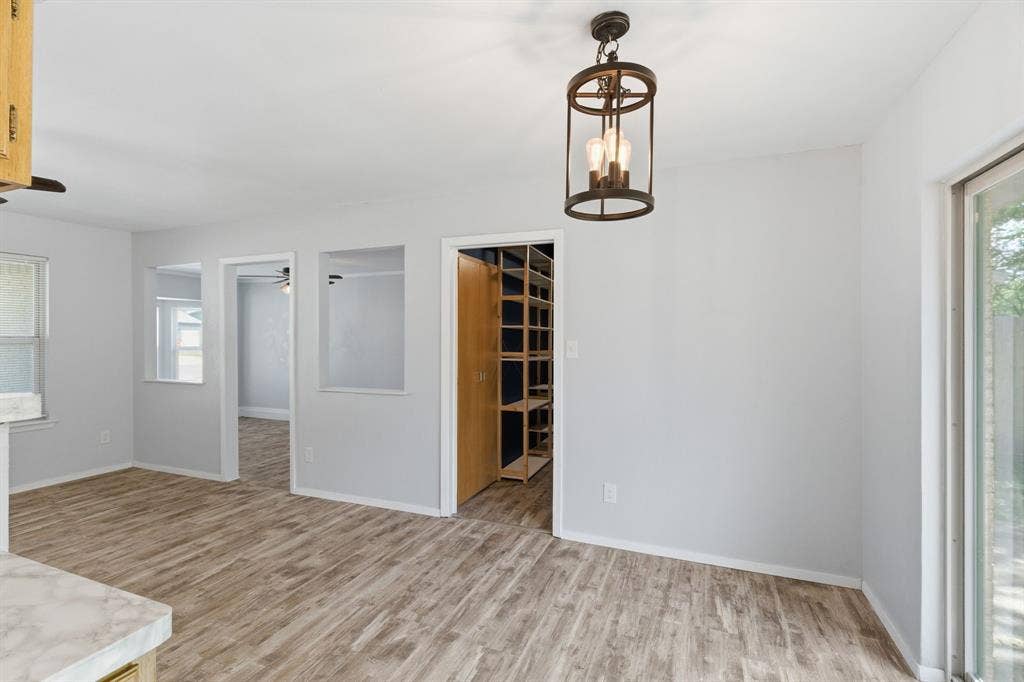 Unfurnished room with light wood finished floors and suspended lighting