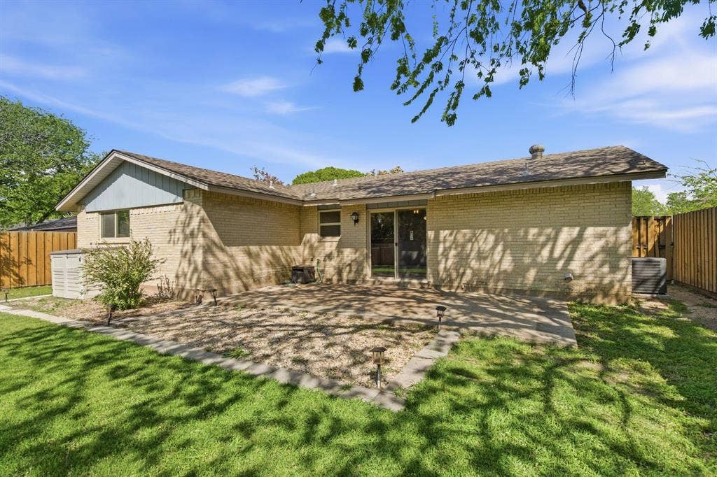 Back of house with brick siding, a fenced backyard, and a patio