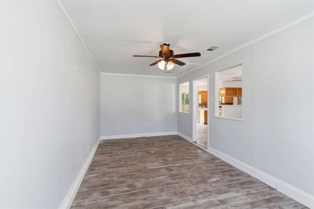 Unfurnished room with wood finished floors, a ceiling fan, and crown molding