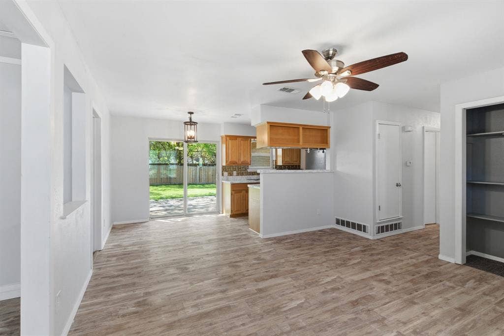 Kitchen featuring light countertops, a ceiling fan, light wood-style floors, hanging light fixtures, and a peninsula