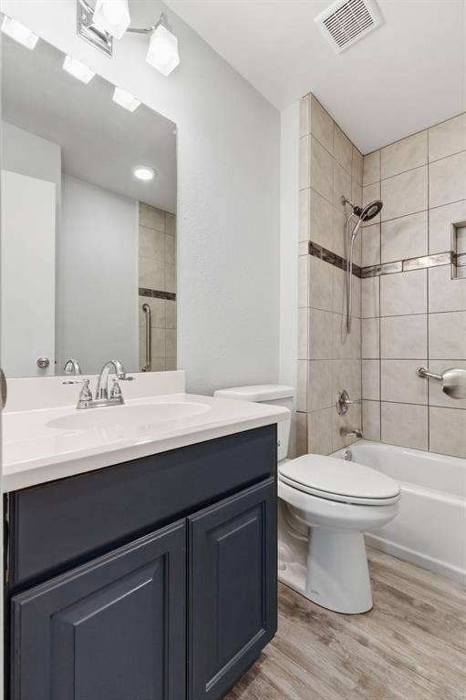 Full bath featuring vanity, washtub / shower combination, and light wood finished floors