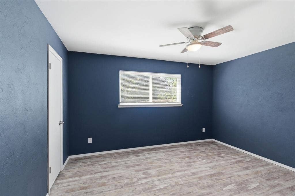 Empty room with light wood finished floors, a ceiling fan, and a textured wall
