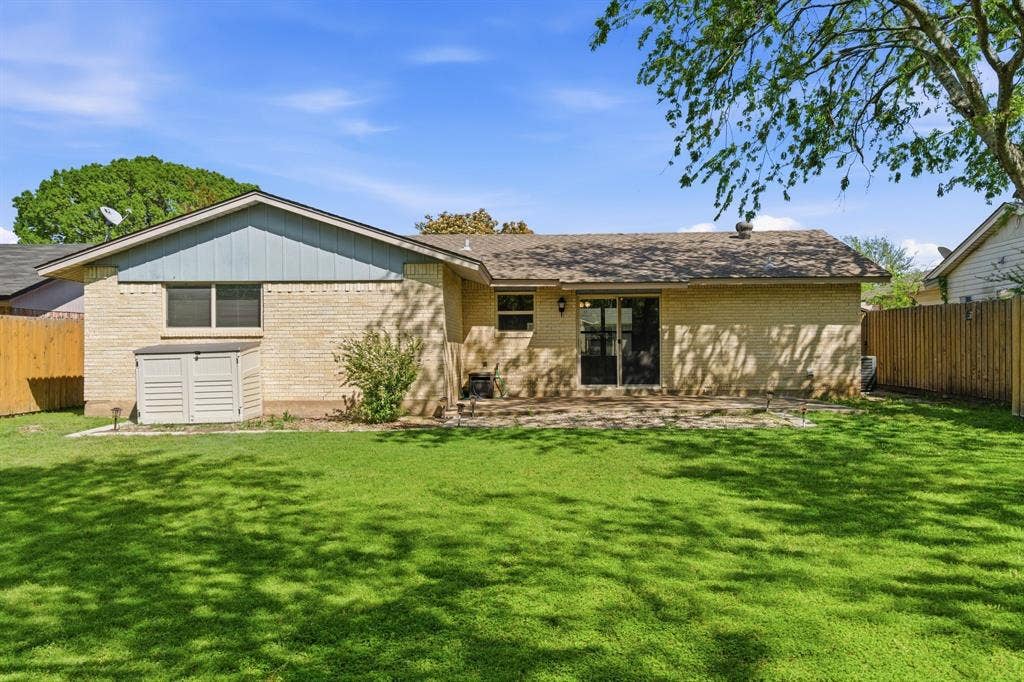 Back of house featuring a fenced backyard, brick siding, and a patio