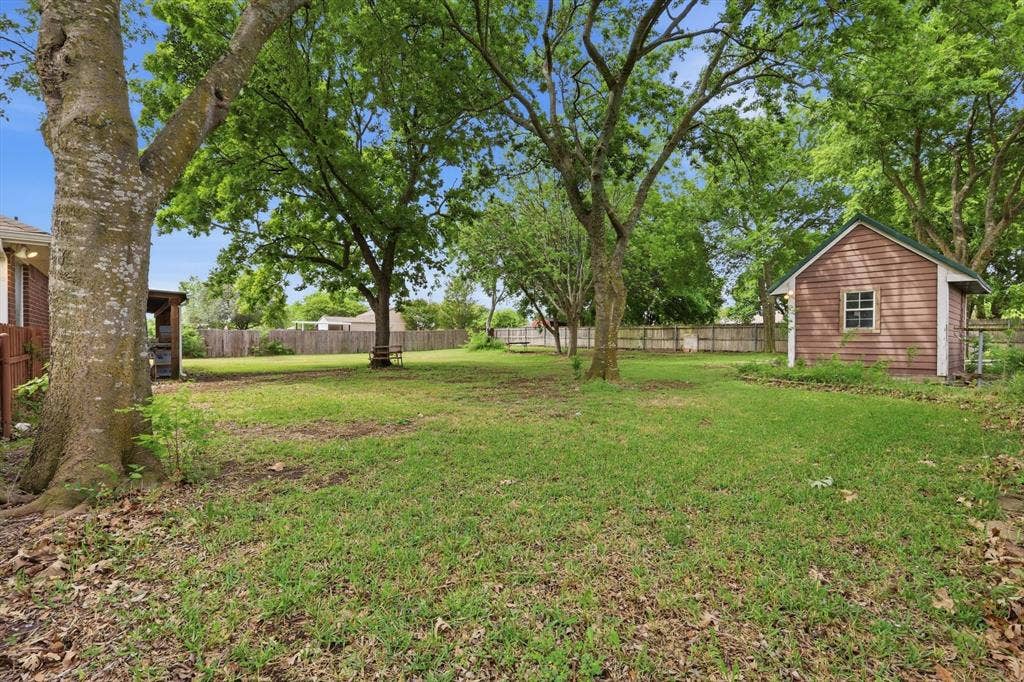 6421 Peak View Court, Midlothian, TX 76065 Another view of the backyard with trees and a shed with electric
