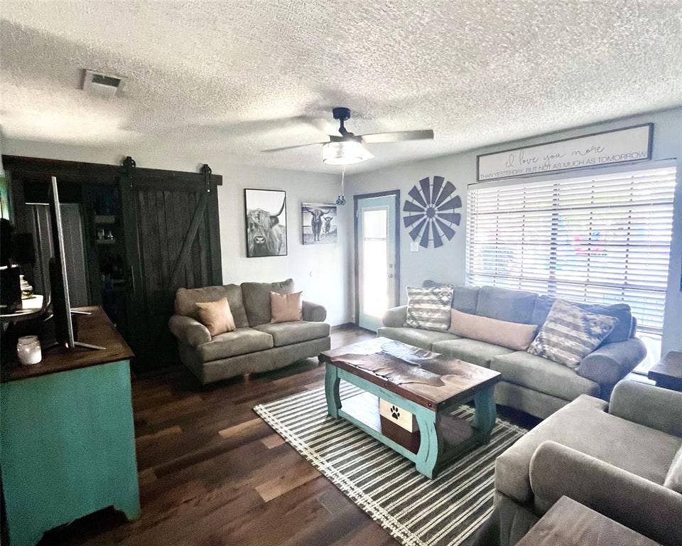 3020 Delaware Trail, Lake Worth, TX 76135 Living area with a textured ceiling, visible vents, wood finished floors, a ceiling fan, and a barn door