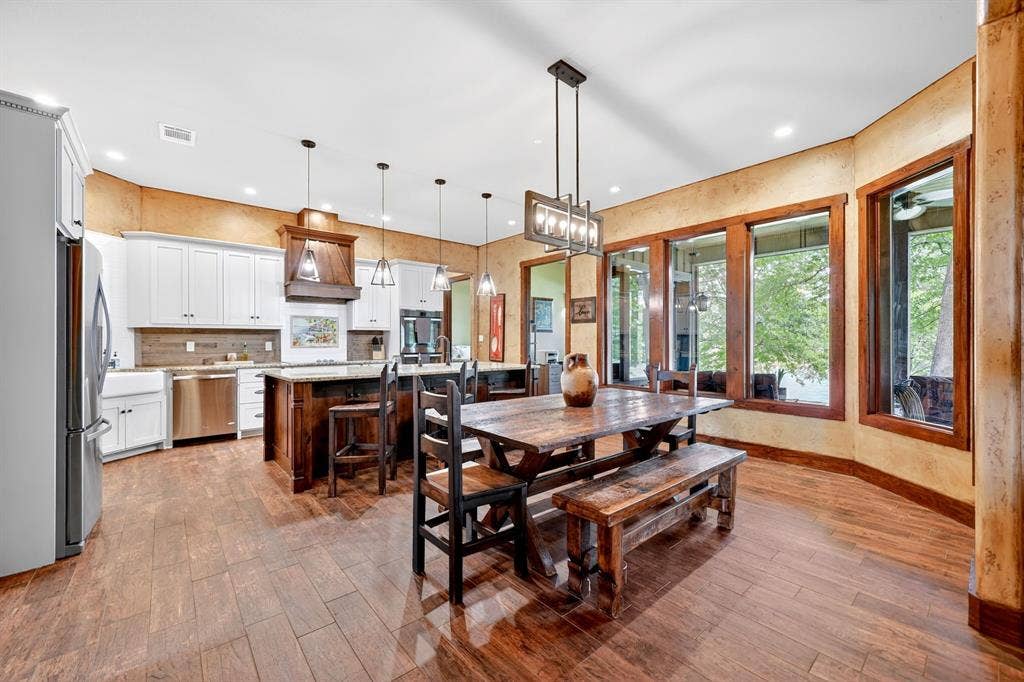15491 Presidio Circle, Caney City, TX 75148 Open-concept kitchen and dining area featuring wood-finish flooring, white cabinetry, a central island with bar seating, and stainless steel appliances