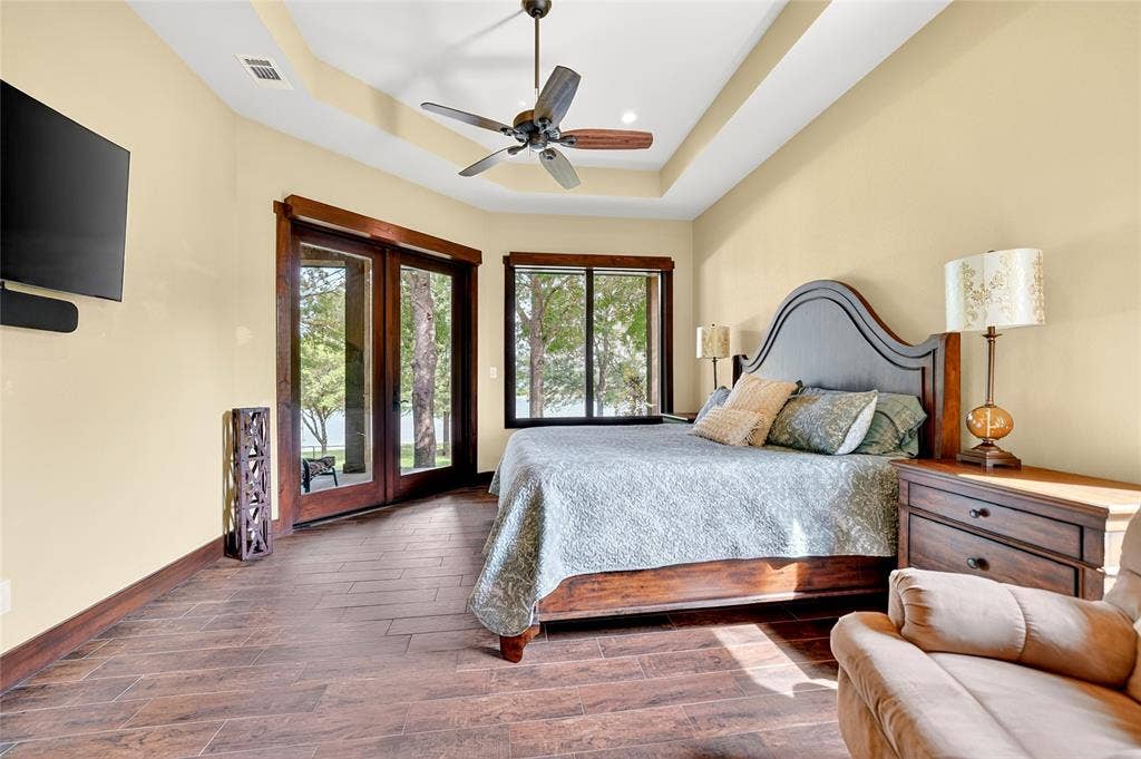 15491 Presidio Circle, Caney City, TX 75148 Bedroom featuring dark wood-finish flooring, a tray ceiling with a ceiling fan, and light-toned walls