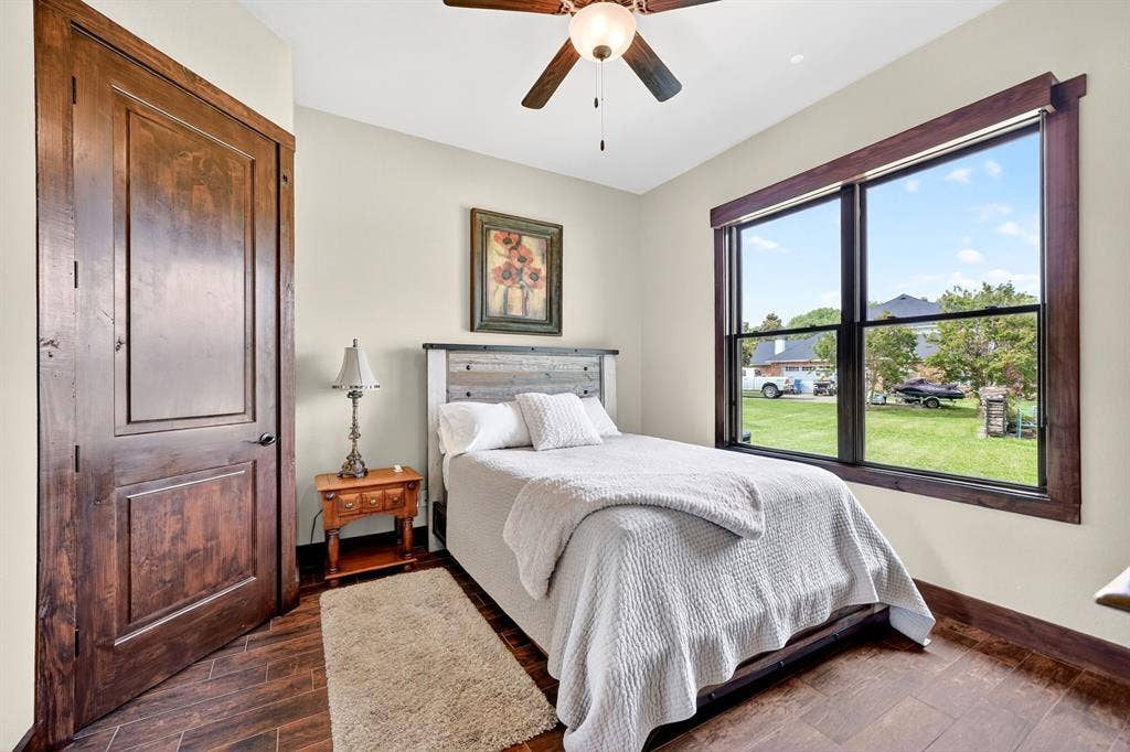 15491 Presidio Circle, Caney City, TX 75148 Interior room featuring wood-finish flooring, a large window with dark trim, a ceiling fan with integrated lighting, a solid wood door, and light-toned walls