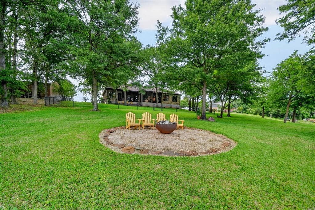 15491 Presidio Circle, Caney City, TX 75148 Expansive green lawn with a circular fire pit area featuring a stone border and a central fire bowl