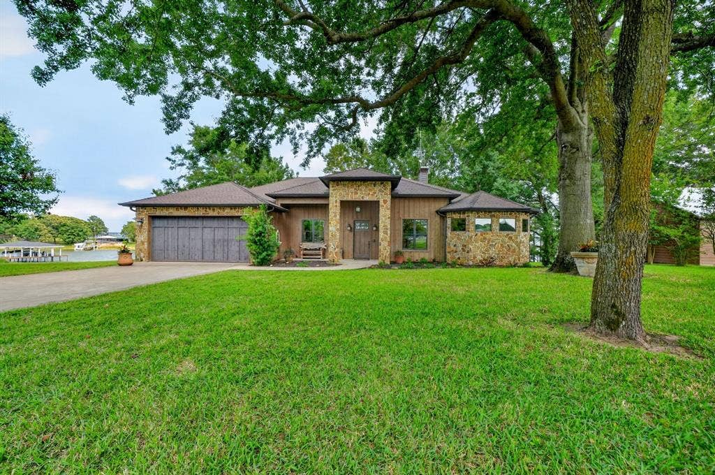 15491 Presidio Circle, Caney City, TX 75148 Stone-clad and wood-sided exterior featuring a two-car garage with wood-finish doors