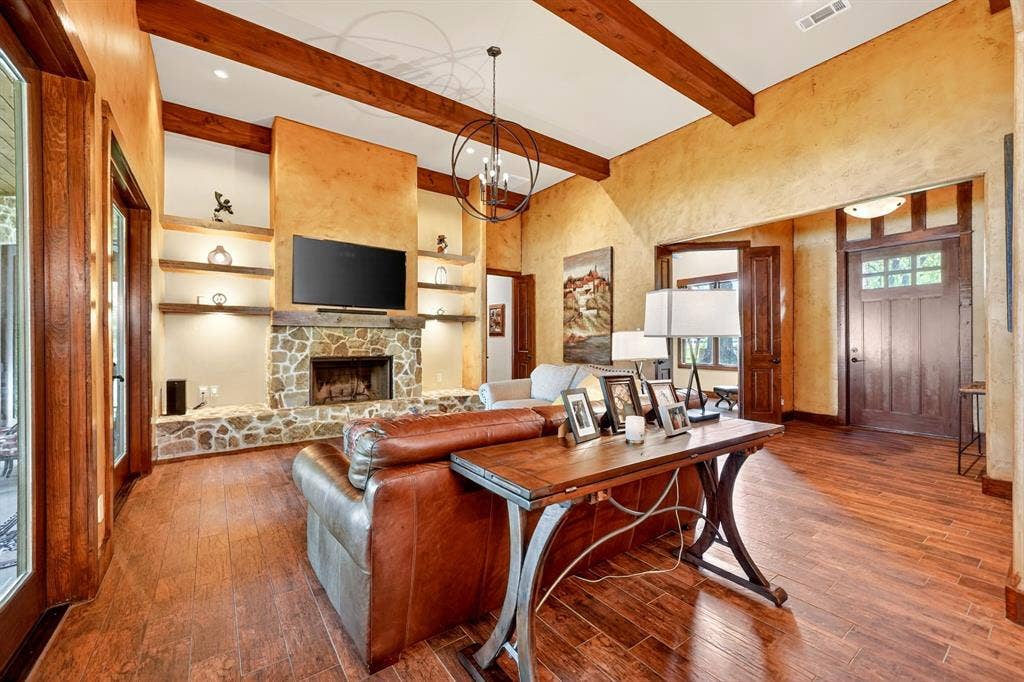 15491 Presidio Circle, Caney City, TX 75148 Living area featuring high vaulted ceilings with exposed wood beams, a stone fireplace with a raised hearth, and built-in shelving with integrated lighting
