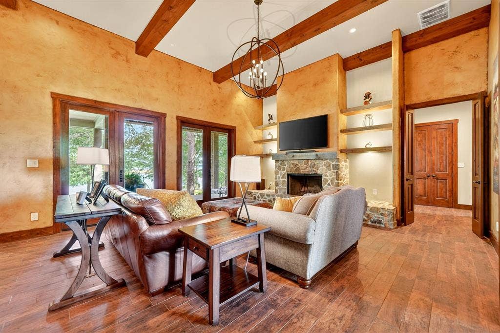 15491 Presidio Circle, Caney City, TX 75148 Living area featuring wood-finish flooring, exposed ceiling beams, and a stone-clad fireplace with built-in shelving