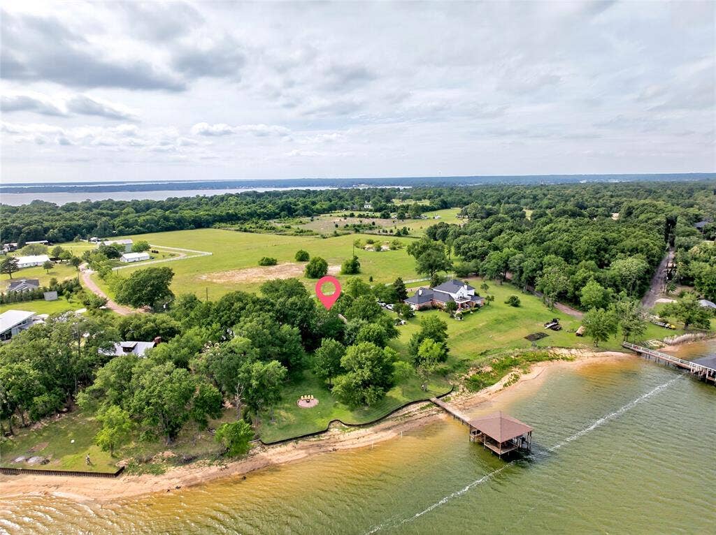 15491 Presidio Circle, Caney City, TX 75148 Expansive waterfront property featuring a private boat dock with a covered slip, sandy shoreline, mature trees, and a spacious green lawn