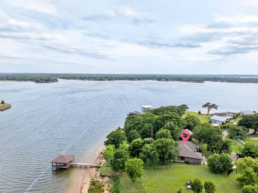 15491 Presidio Circle, Caney City, TX 75148 Waterfront property featuring a private boat dock with covered slip, expansive body of water, lush green lawn, and mature trees