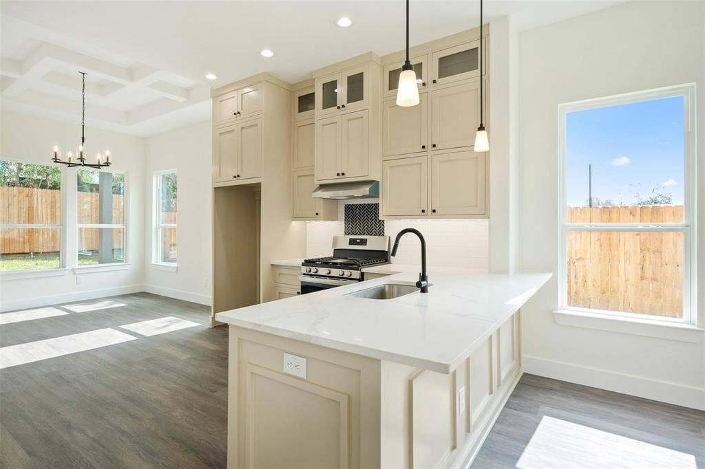 802.5 N Needmore Street, Athens, TX 75751 Kitchen featuring cream cabinetry, coffered ceiling, stainless steel gas range, light stone countertops, and dark wood-style floors